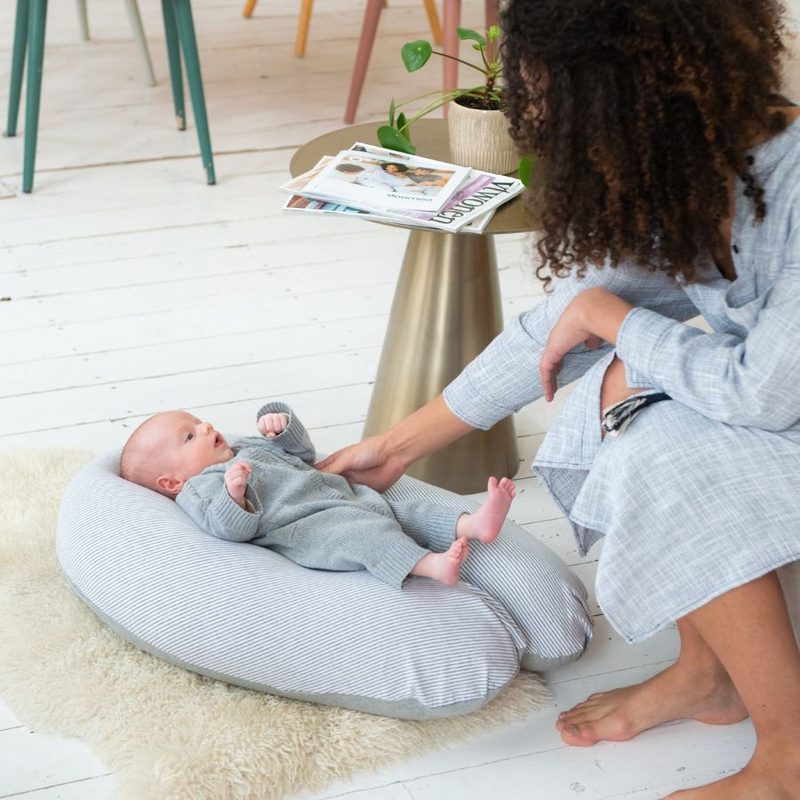 Maman qui installe son nouveau-né sur un réducteur de lit douillet dans le salon