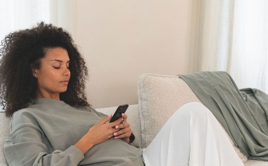 Future maman détendue sur son canapé avec son coussin de grossesse