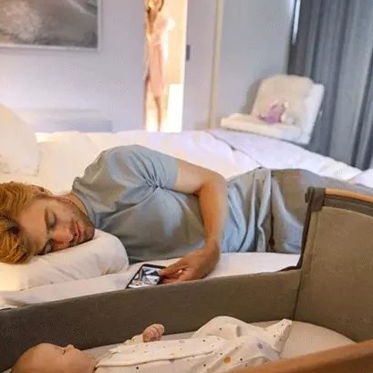 Papa endormi à côté de son bébé couché dans un berceau cododo