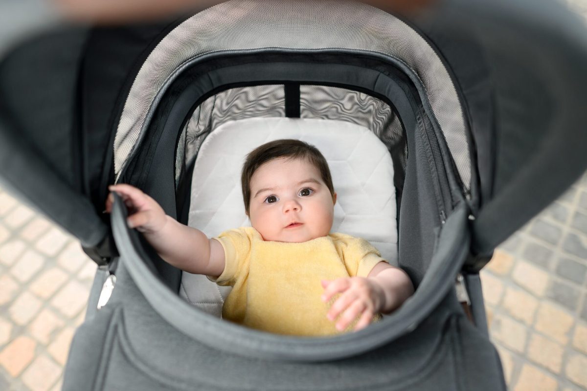 Bébé souriant bien installé dans sa poussette haut de gamme