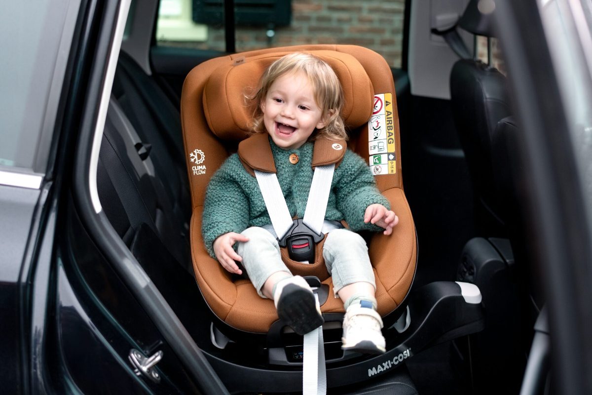 Petit garçon souriant installé dans son siège auto Maxi-Cosi