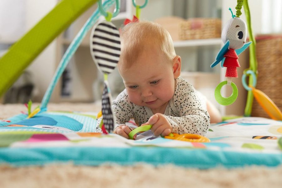 Bébé qui joue sous l'arche de son tapis d'éveil