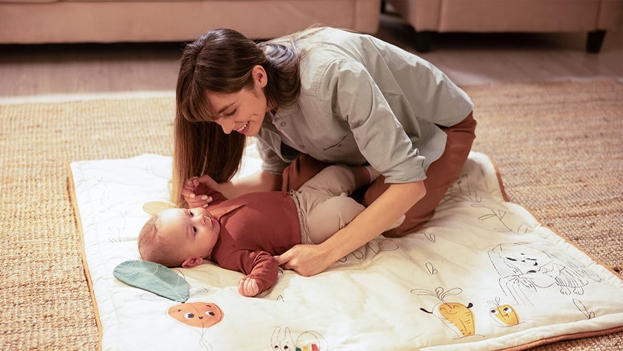 Maman qui joue avec son bébé allongé sur un tapis d'éveil
